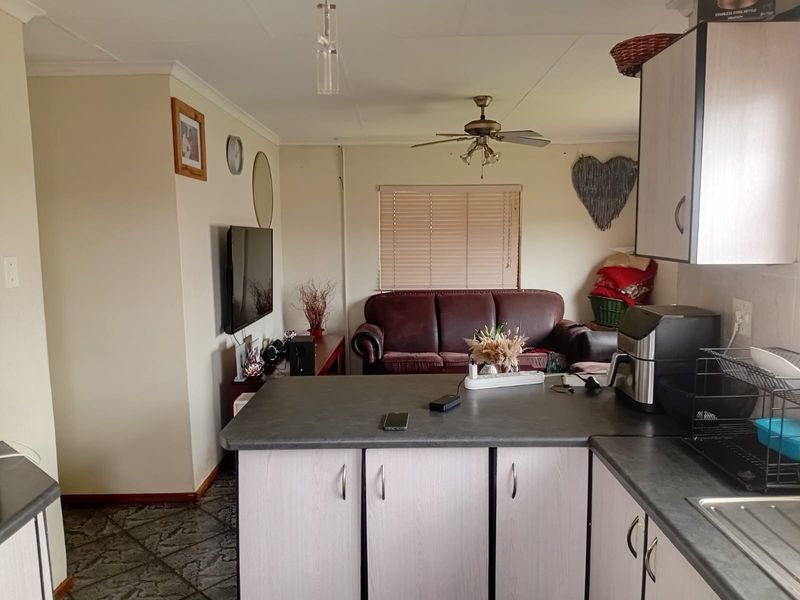 Open plan kitchen and living area featuring laminate countertops, cabinetry, tiled flooring, and a ceiling fan.