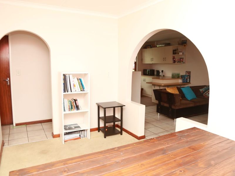 Open plan living area featuring arched doorways, tiled flooring, and a connected kitchen space with built-in cabinetry and a breakfast counter.