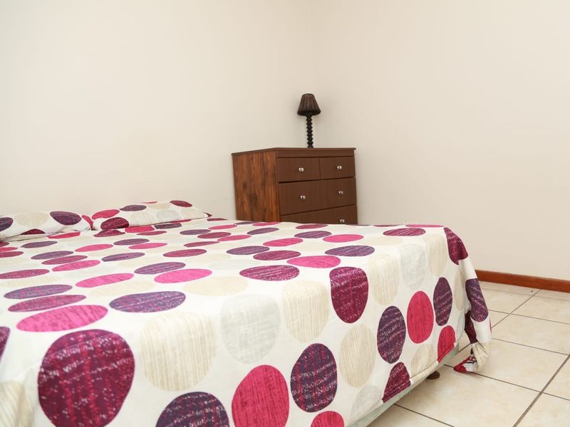 A simple bedroom featuring neutral wall finishes and tiled flooring, providing a functional and clean space.