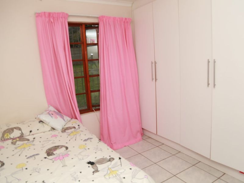 A bedroom featuring built-in cupboards, tiled flooring, and a wooden window frame, providing a functional and practical living space.