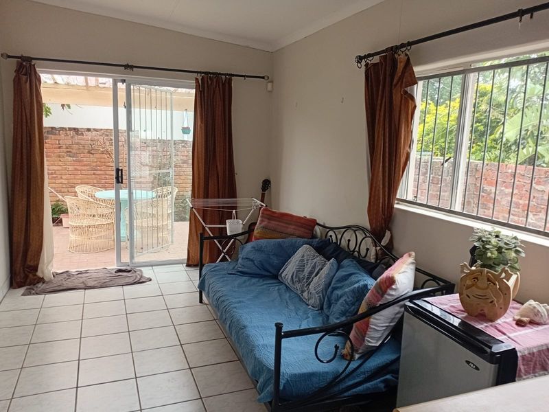 A living room featuring tiled flooring, a sliding glass door leading to a patio, and a window with security bars.