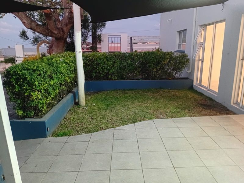 A private patio area featuring tiled flooring, a raised garden bed, and a shade sail, providing direct access to the interior living space.