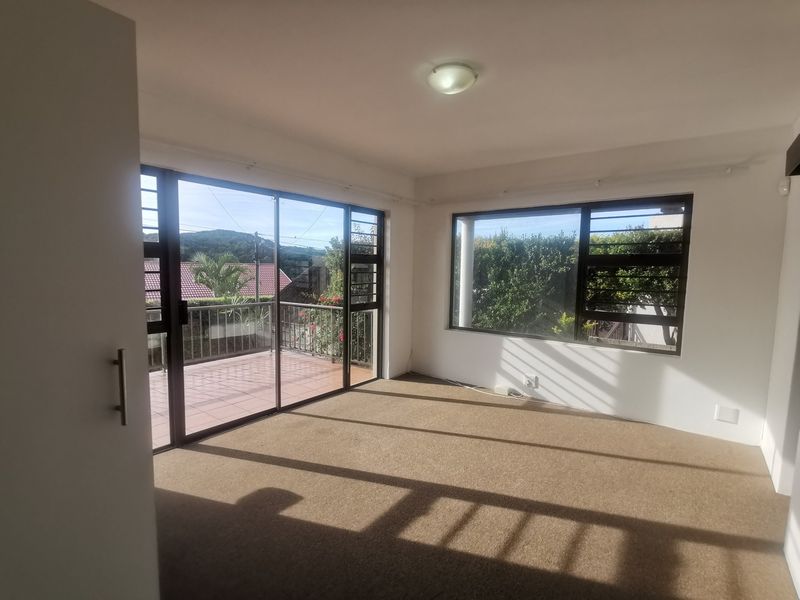 Bright and spacious bedroom featuring carpeted flooring, built-in cupboards, and large sliding doors leading to an outdoor balcony area.