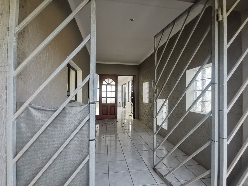 An entrance hall featuring tiled flooring, security gates, and glass block windows, leading into the main living area of the property.