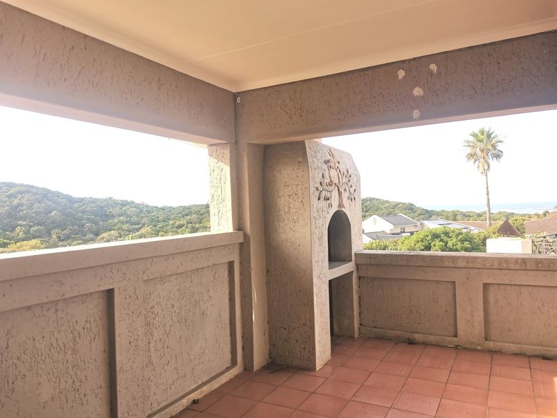 Covered balcony featuring a built-in braai, tiled flooring, and panoramic views of the surrounding landscape and coastline.