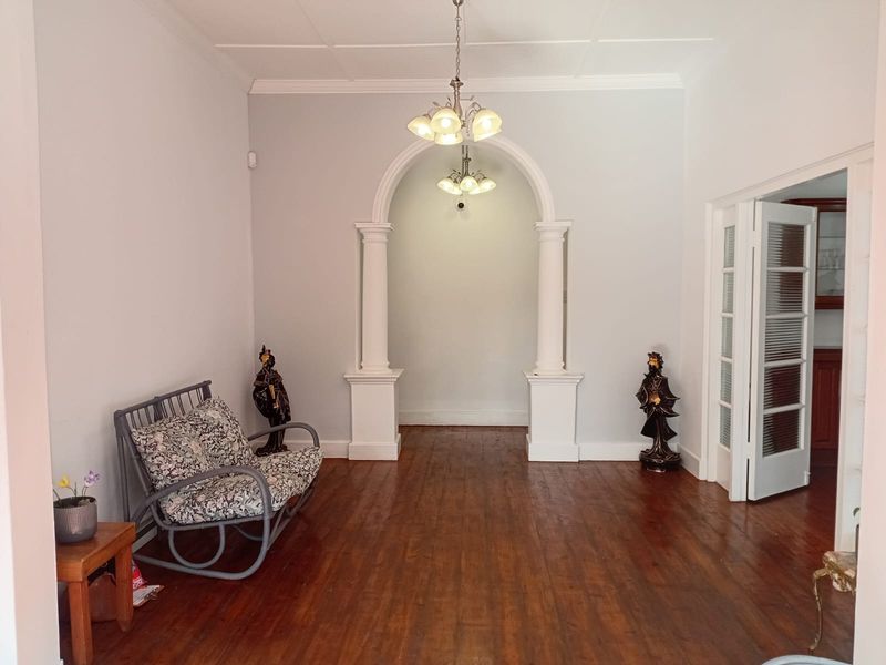 A spacious living area featuring polished hardwood floors, a decorative arched entryway with columns, and elegant crown molding.
