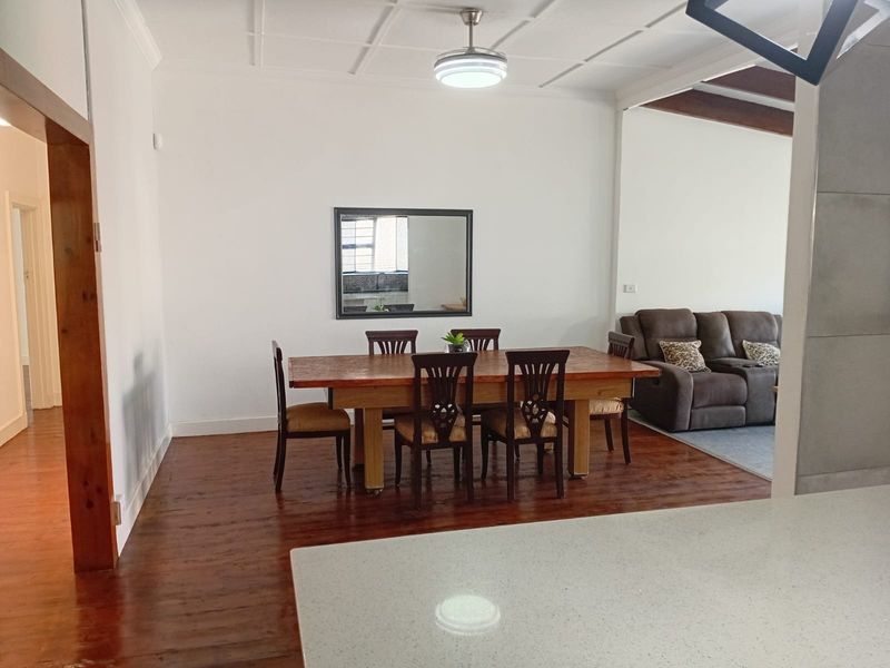 Open plan dining and living area featuring polished hardwood flooring, a coffered ceiling with a fan, and a modern kitchen island countertop.