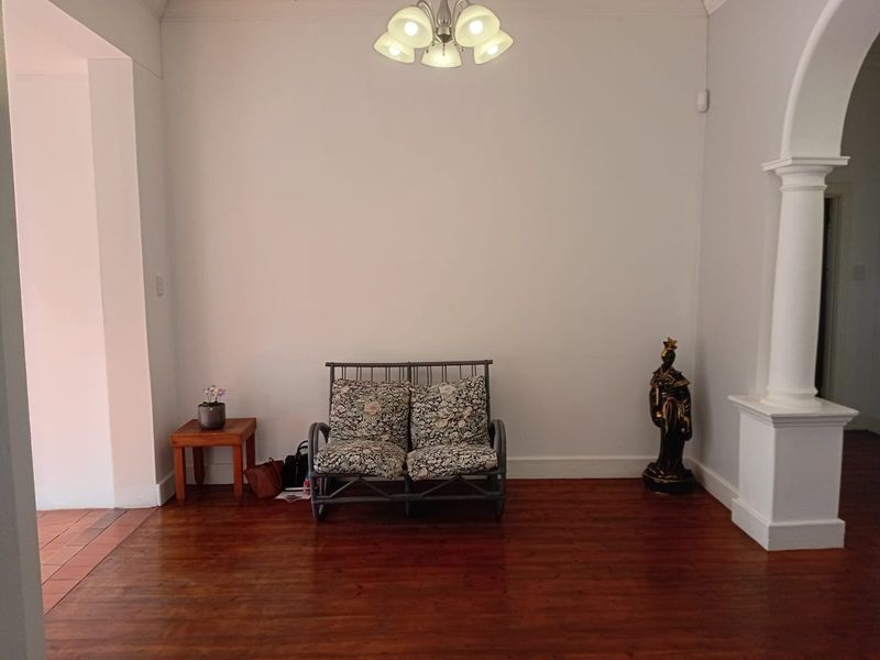 A living room area featuring polished hardwood flooring, a decorative archway, and a central ceiling light fixture.
