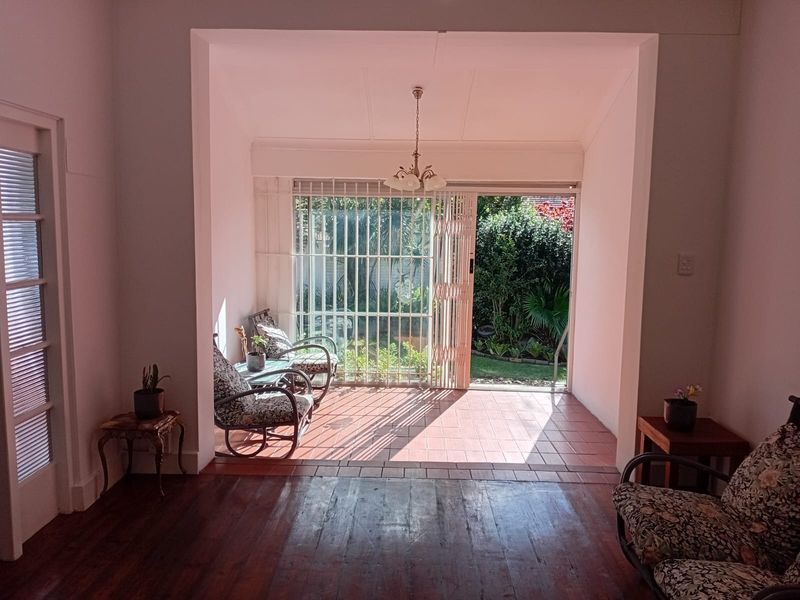 A covered patio area featuring tiled flooring, security gates, and direct access to the garden, providing a seamless transition between indoor and outdoor living spaces.