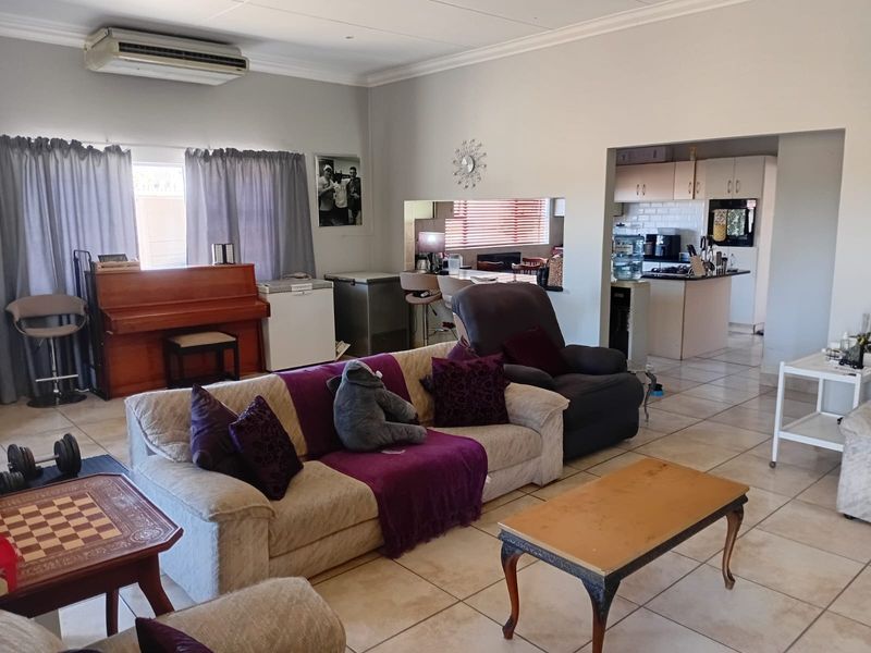 Open plan living area featuring tiled floors and a connected kitchen with built-in cabinetry and appliances, offering a functional layout for daily living.