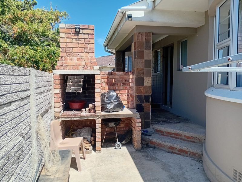 Outdoor patio area featuring a built-in brick braai, concrete flooring, and direct access to the main house structure.