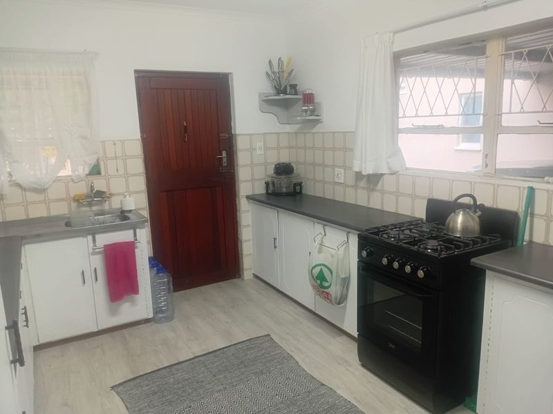 Functional kitchen featuring white cabinetry, laminate countertops, a gas stove, and a tiled backsplash with direct access to the exterior.