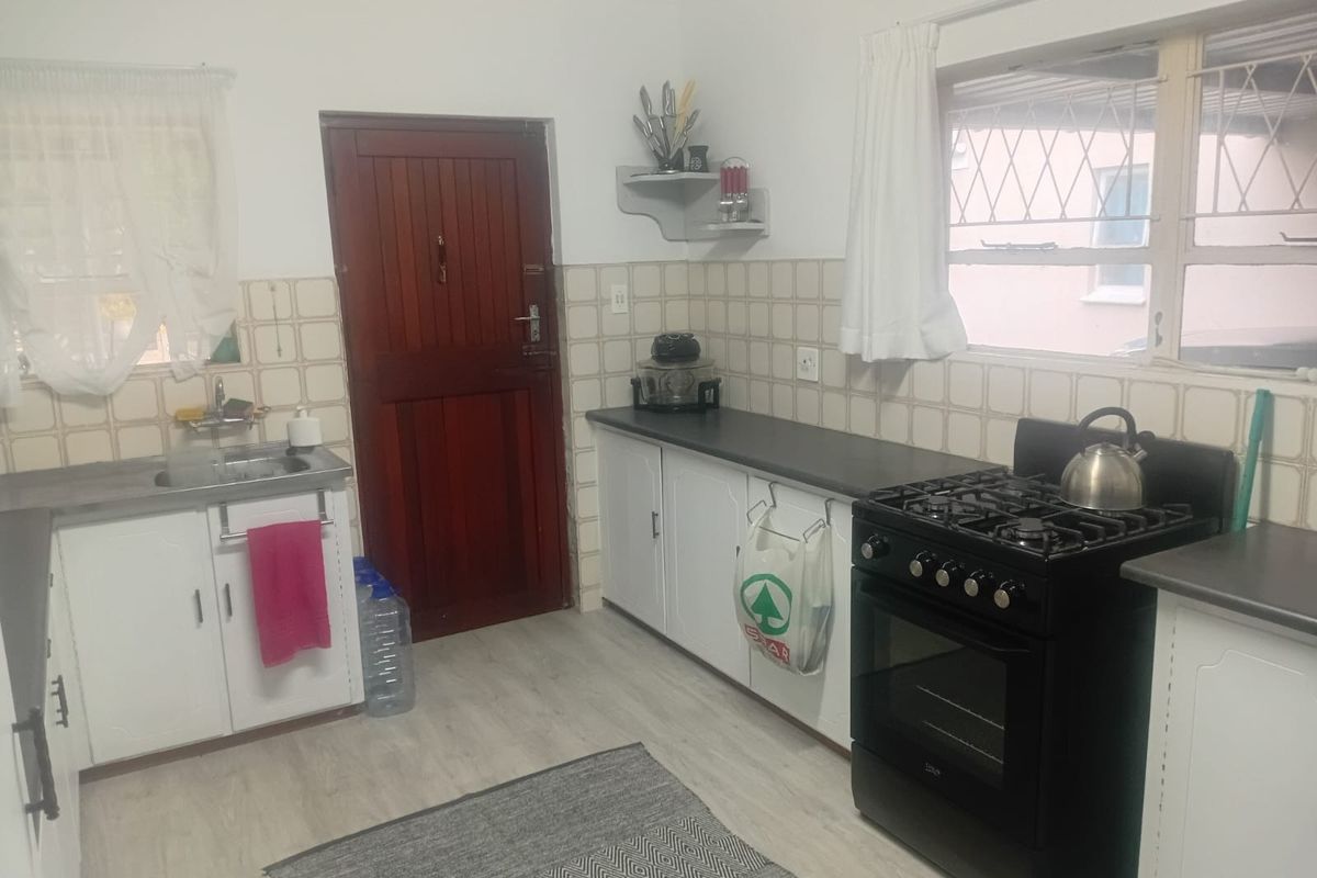 Functional kitchen featuring white cabinetry, laminate countertops, a gas stove, and a tiled backsplash with direct access to the exterior.