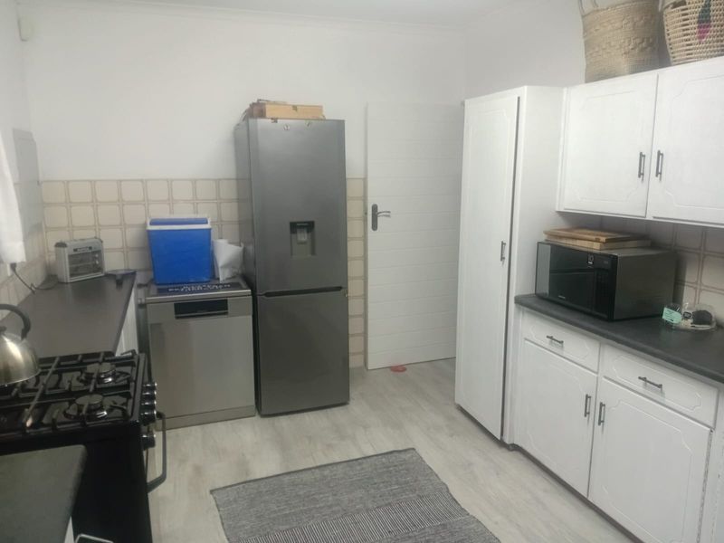 A functional kitchen featuring white cabinetry, a gas stove, tiled backsplash, and light-toned laminate flooring.