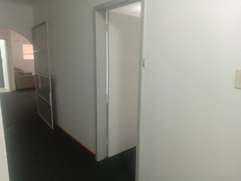 A simple interior hallway featuring white walls, internal doors, and a security gate, providing access to adjacent rooms within the apartment.