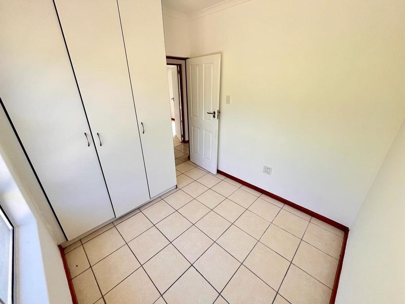 A clean, empty bedroom featuring neutral tiled flooring and built-in cupboards, offering a blank canvas for personalization.