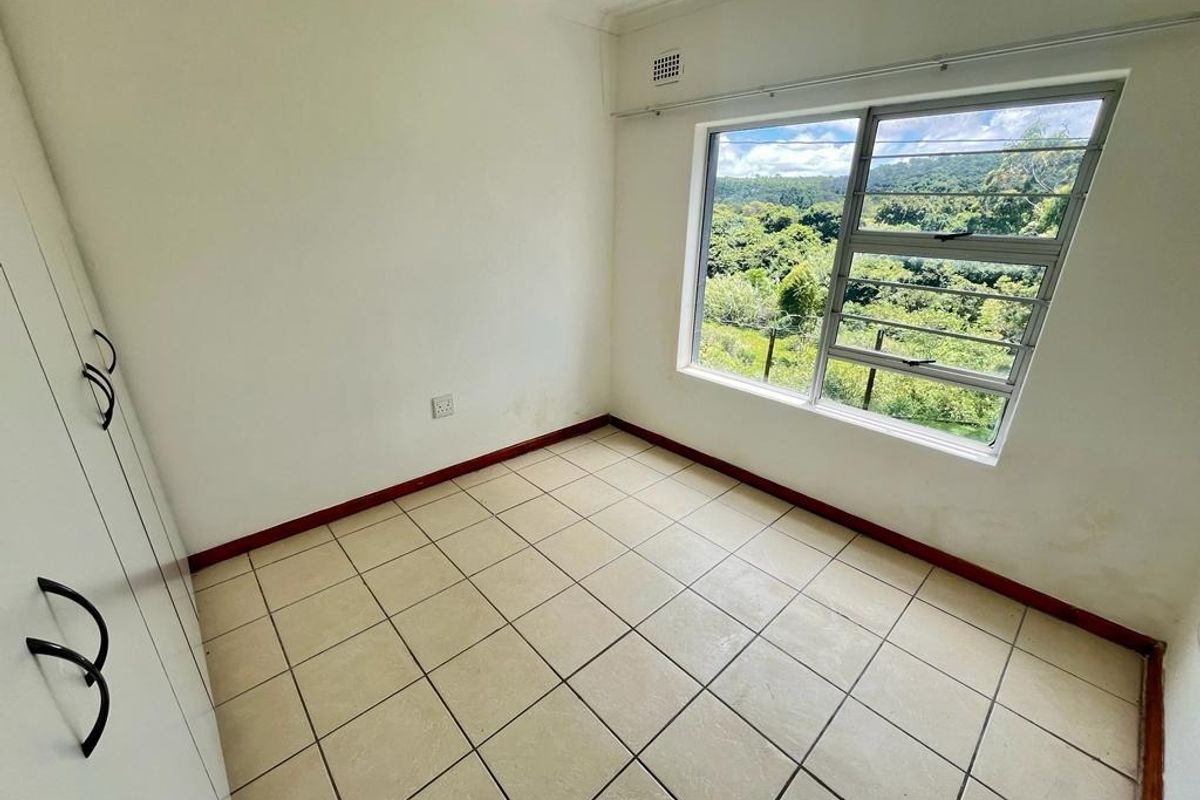 A vacant bedroom featuring tiled flooring, built-in cupboards, and a large window with scenic views.
