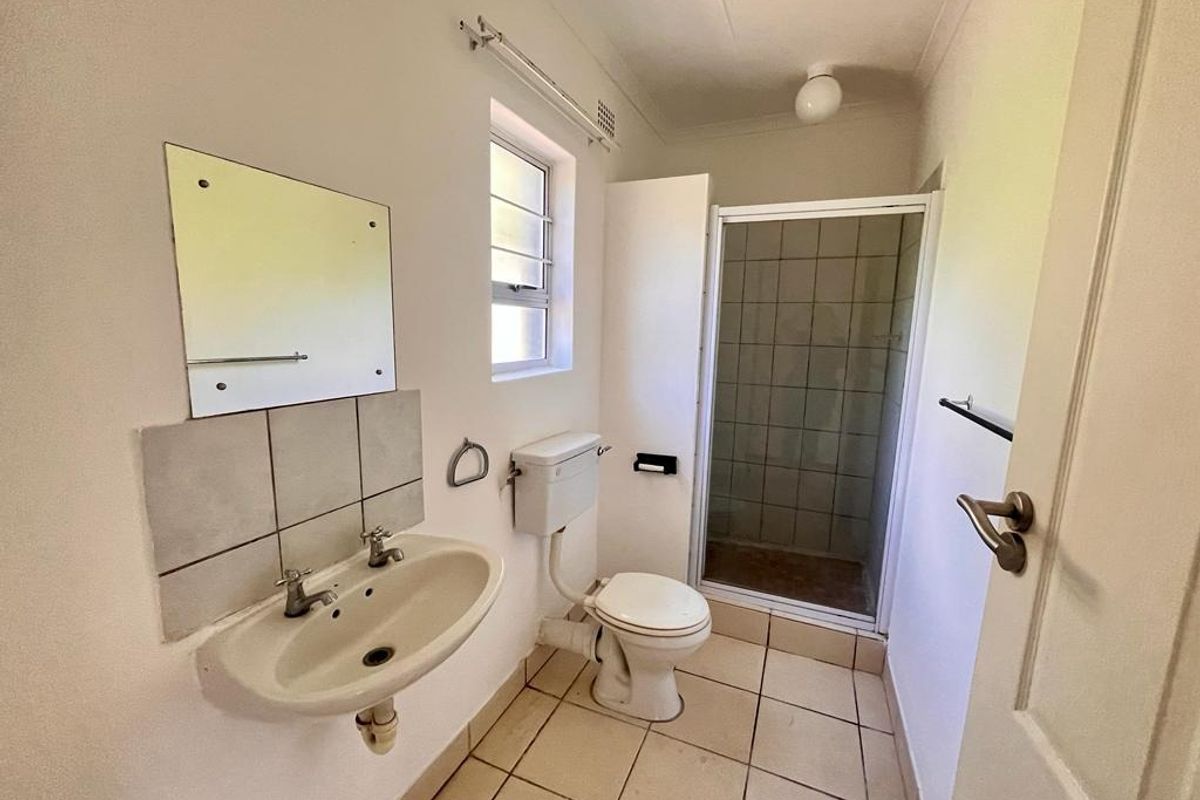 A functional bathroom featuring a pedestal basin, toilet, and a separate shower enclosure with tiled flooring.