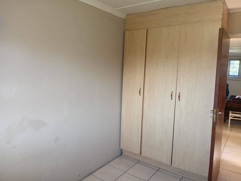 A bedroom featuring built-in cupboards and tiled flooring, presenting a clean, empty space ready for personalization.