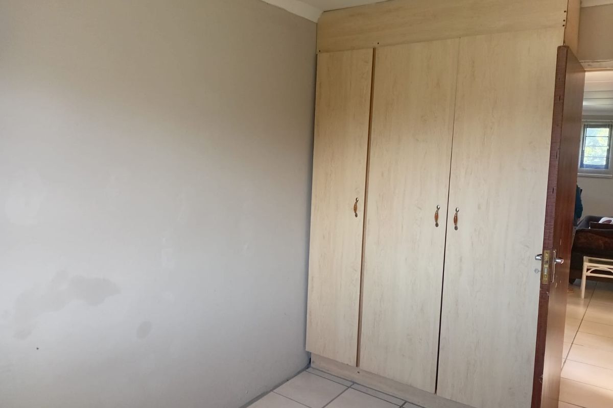 A bedroom featuring built-in cupboards and tiled flooring, presenting a clean, empty space ready for personalization.