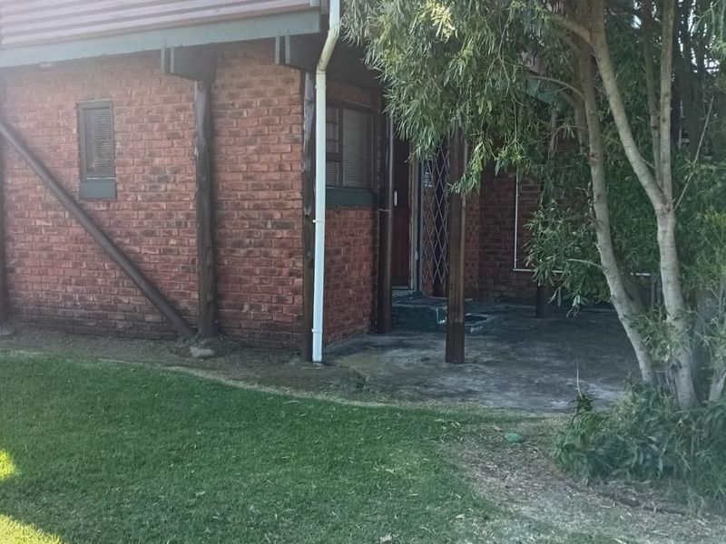 Rear exterior view of the flat featuring a brick facade, concrete patio area, and security gate entrance.