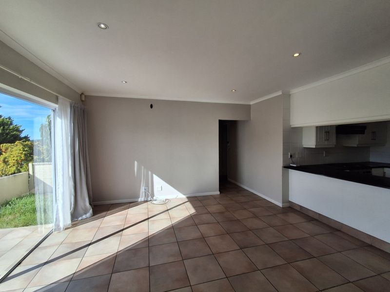 Open plan living area featuring tiled floors, recessed lighting, and direct access to the garden through a sliding glass door, adjacent to the kitchen.