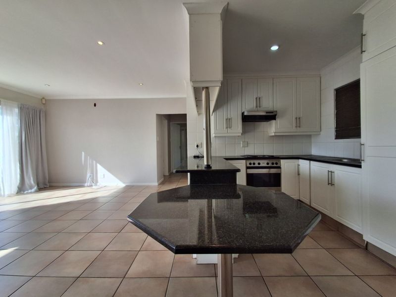 Spacious open-plan kitchen and living area featuring tiled floors, granite countertops, and built-in cabinetry, offering a bright and functional layout.