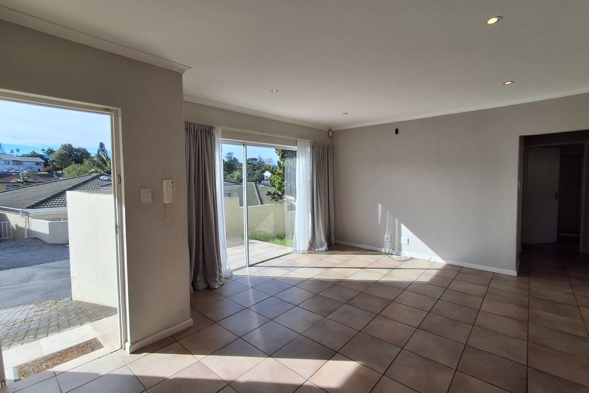 Spacious, light-filled living area featuring neutral tiled flooring, recessed downlights, and direct access to an outdoor patio through sliding glass doors.
