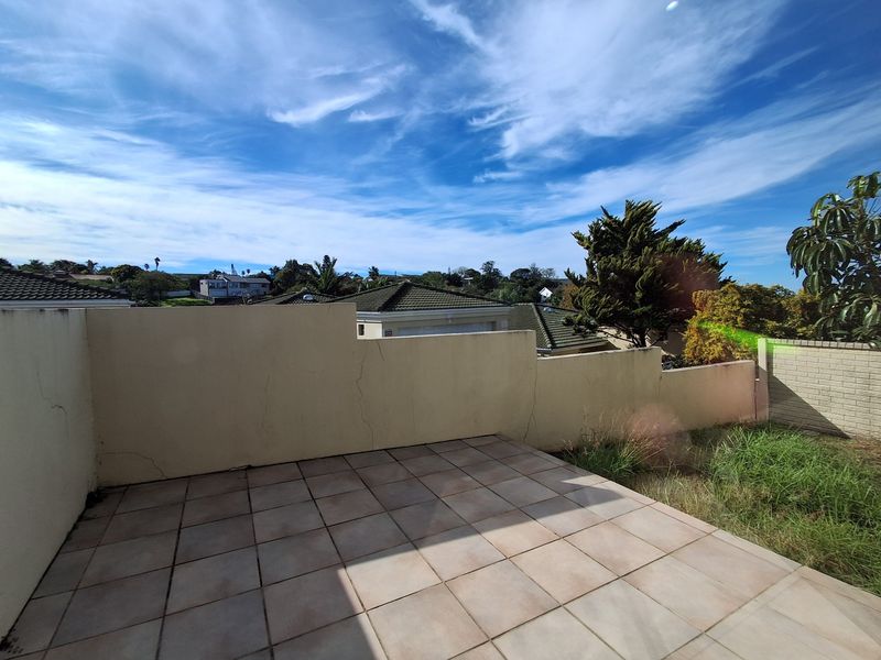 An outdoor tiled patio area featuring a boundary wall with visible structural cracking, overlooking the surrounding residential neighborhood.