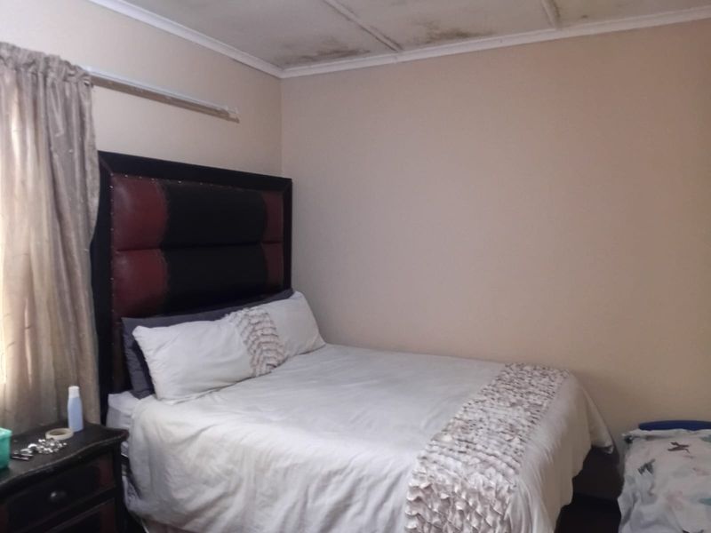 A bedroom featuring a standard layout with visible water damage and staining on the ceiling, requiring maintenance and cosmetic repair.