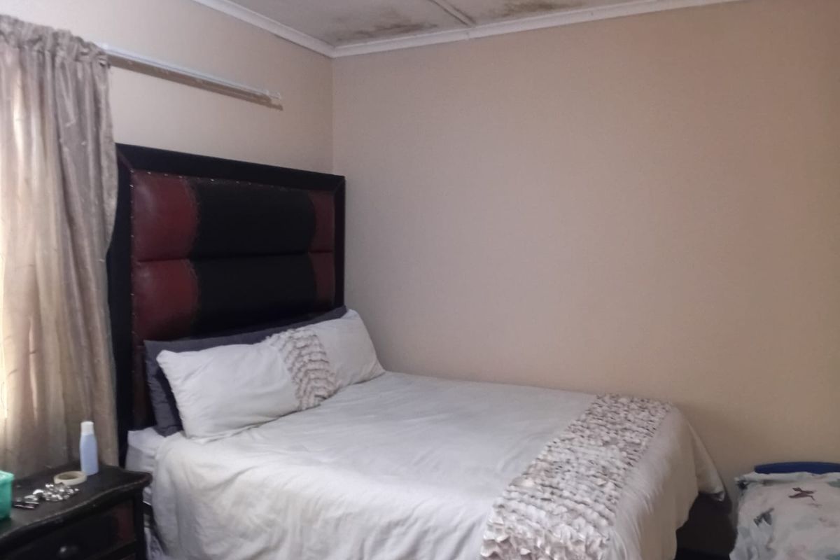 A bedroom featuring a standard layout with visible water damage and staining on the ceiling, requiring maintenance and cosmetic repair.