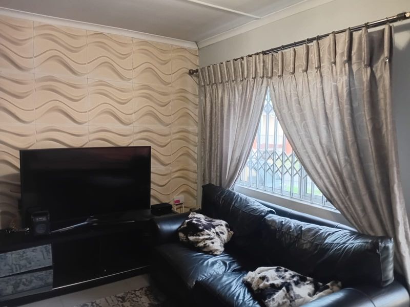 A living room featuring a textured accent wall, window with security gate, and curtain fixtures.
