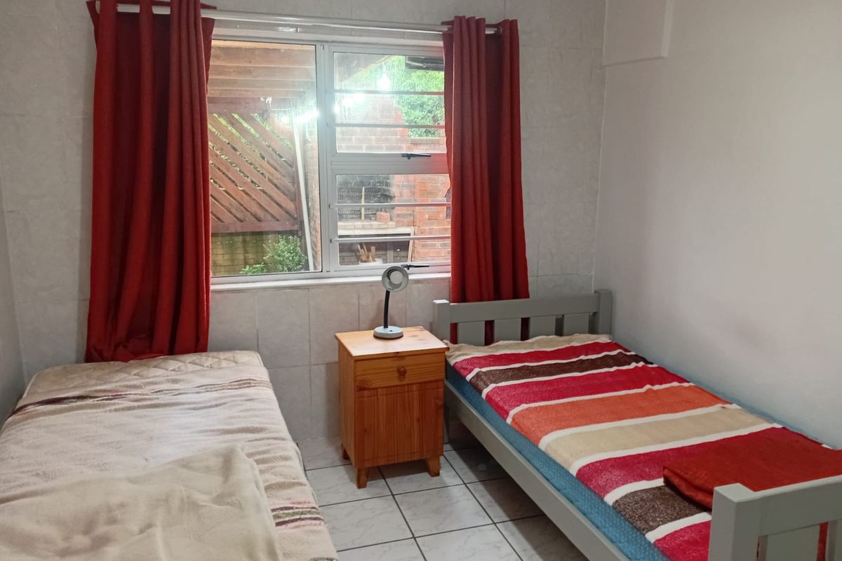 A functional bedroom featuring tiled flooring and a window with an exterior view.