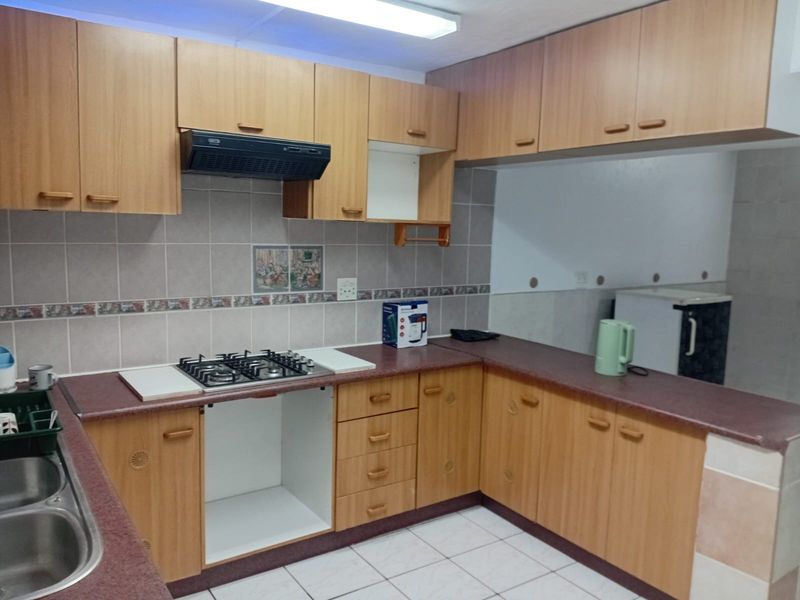 Functional kitchen featuring laminate cabinetry, gas hob with extractor fan, double bowl sink, and tiled splashback, offering a practical layout for daily use.