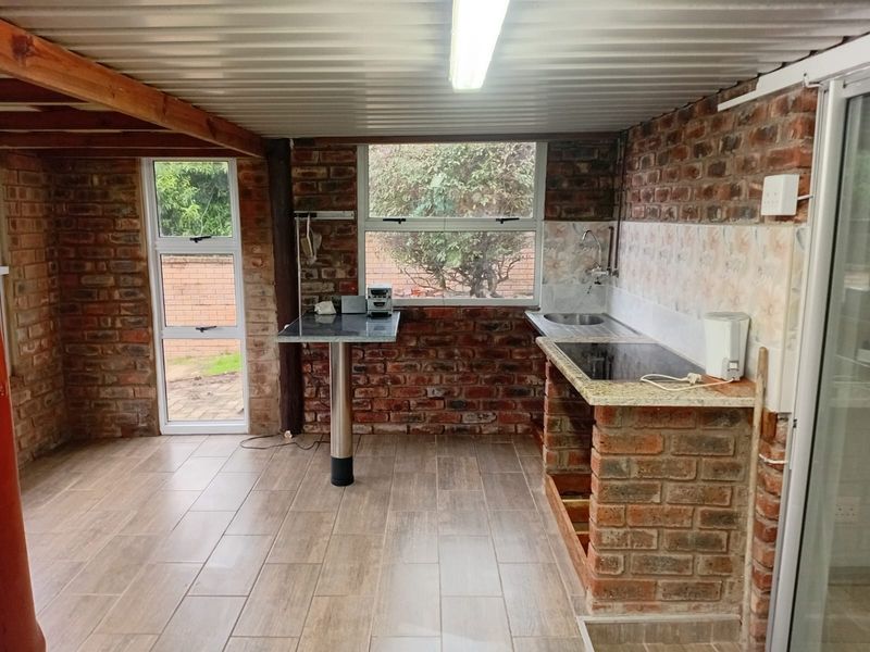 A rustic kitchen area featuring exposed brick walls, granite countertops, and a built-in brick base, offering a unique industrial aesthetic ready for modernization.
