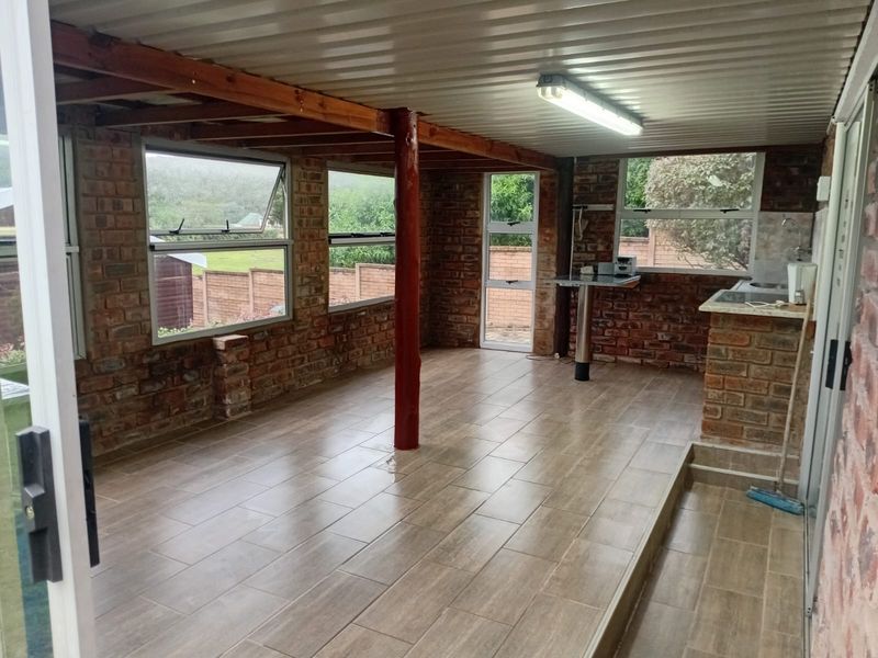 A spacious covered patio area featuring exposed brick walls, tiled flooring, and a built-in brick counter, offering a versatile outdoor living space.