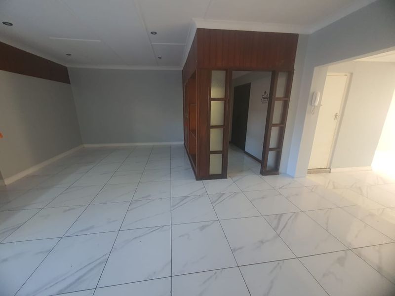 Spacious living area featuring modern marble-look floor tiles, recessed lighting, and a distinctive built-in wooden room divider.
