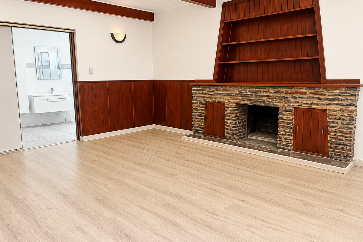 Spacious living room featuring a stone fireplace, built-in wooden shelving, and classic wood paneling, with direct access to an adjacent modern bathroom.