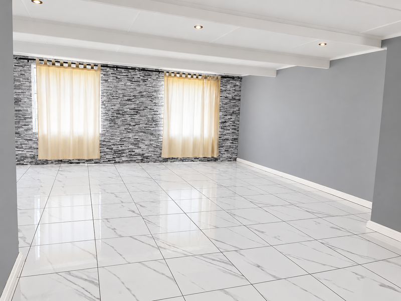 A spacious, empty living area featuring modern marble-look floor tiles, a textured stone feature wall, exposed ceiling beams, and recessed downlighting.