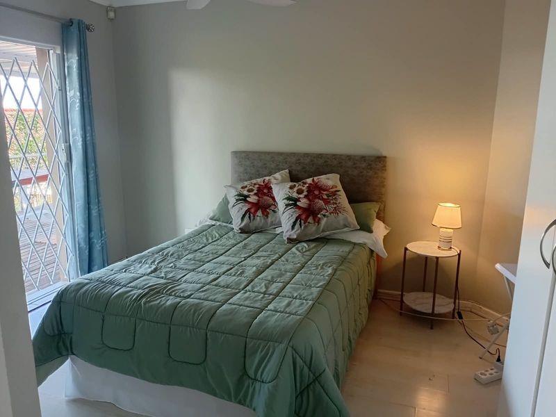 A bedroom featuring a sliding door with a security gate leading to an outdoor area and a ceiling fan.
