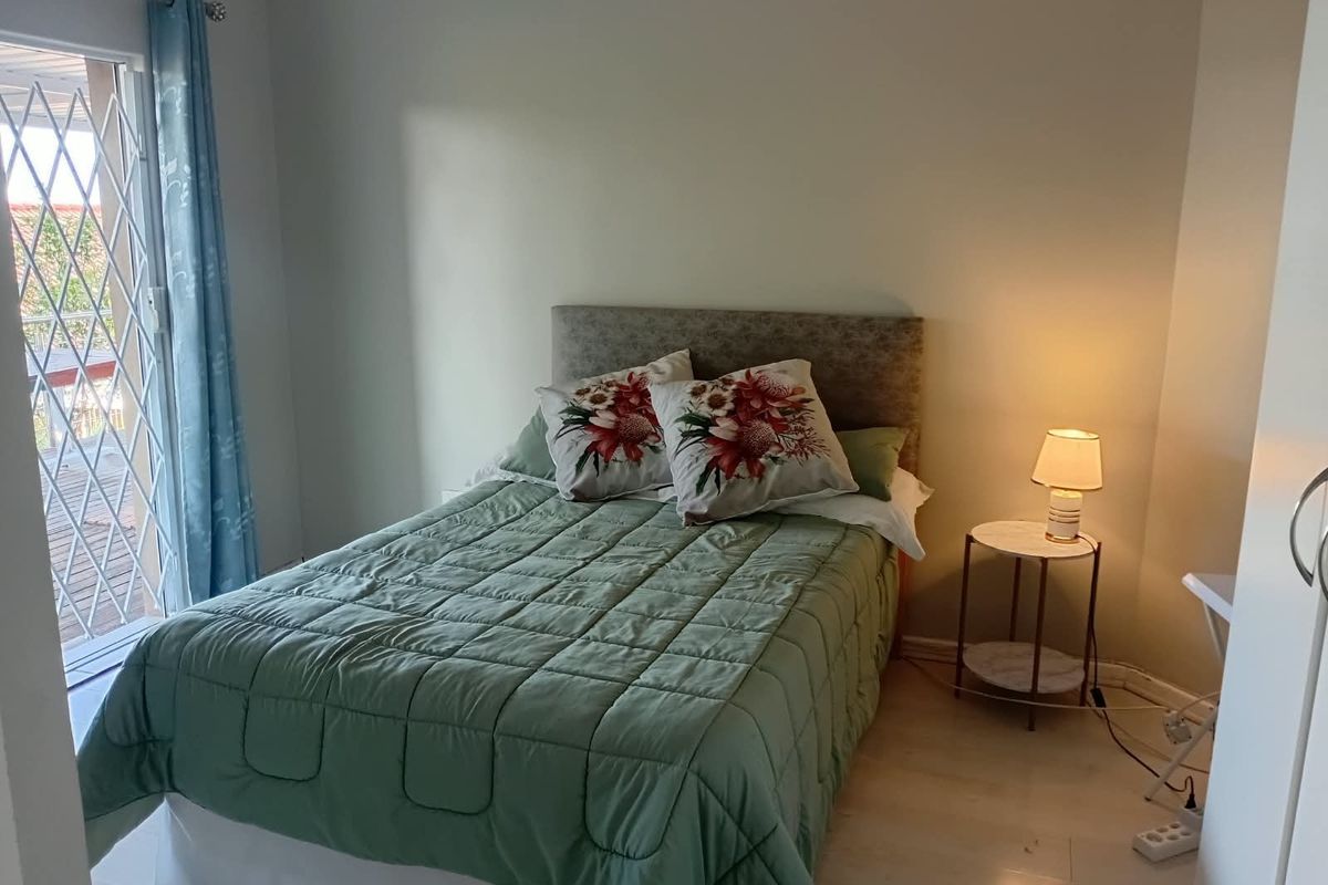 A bedroom featuring a sliding door with a security gate leading to an outdoor area and a ceiling fan.