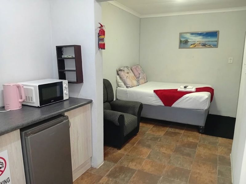 An open-plan studio apartment featuring a kitchenette area with built-in cabinetry and a combined sleeping space with tiled flooring.