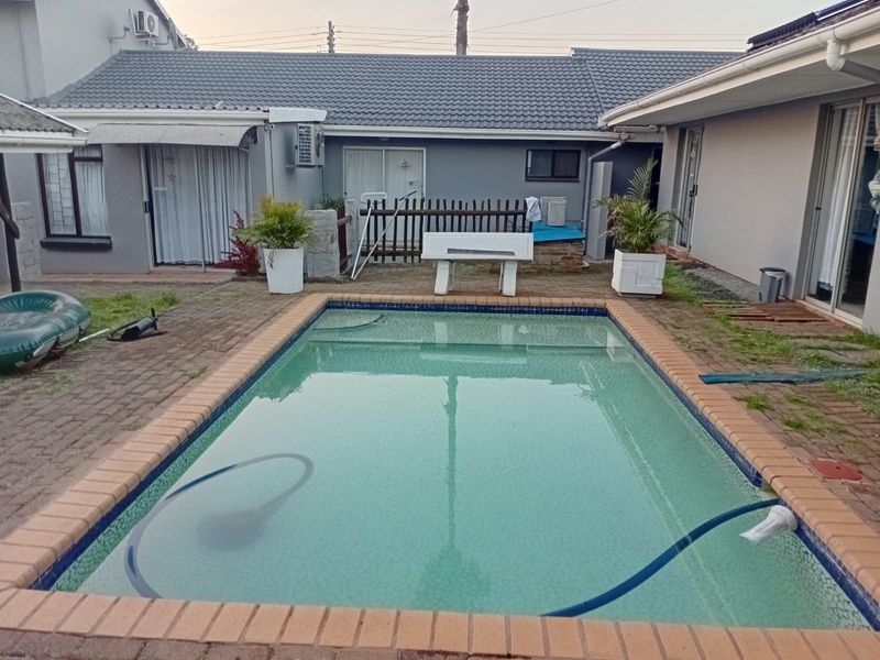 Outdoor pool area featuring a rectangular swimming pool with brick paving surround, set within a private courtyard with access to the main dwelling.
