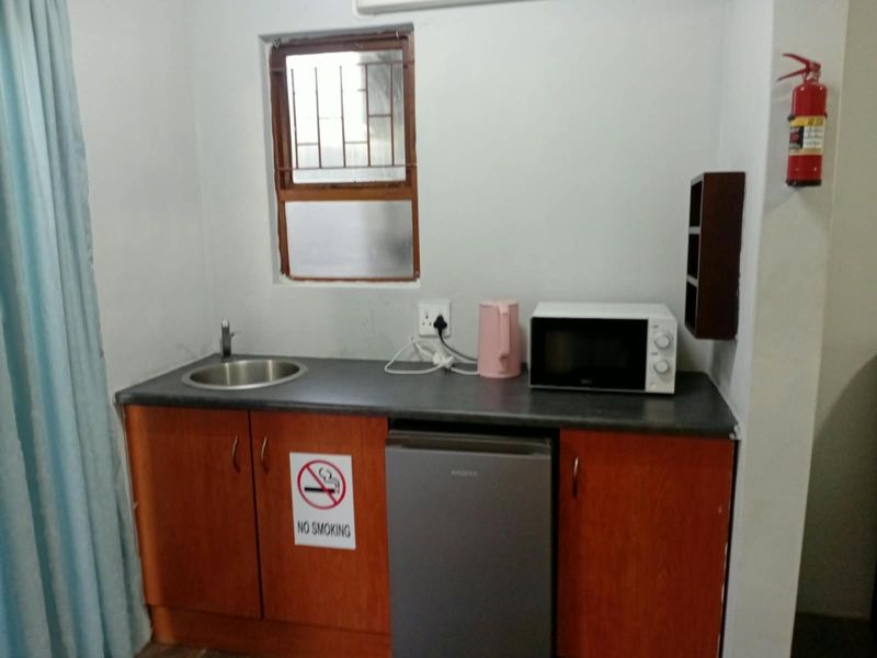 Compact kitchenette featuring built-in wooden cabinetry, a stainless steel sink, and a functional countertop area with a window for natural light.