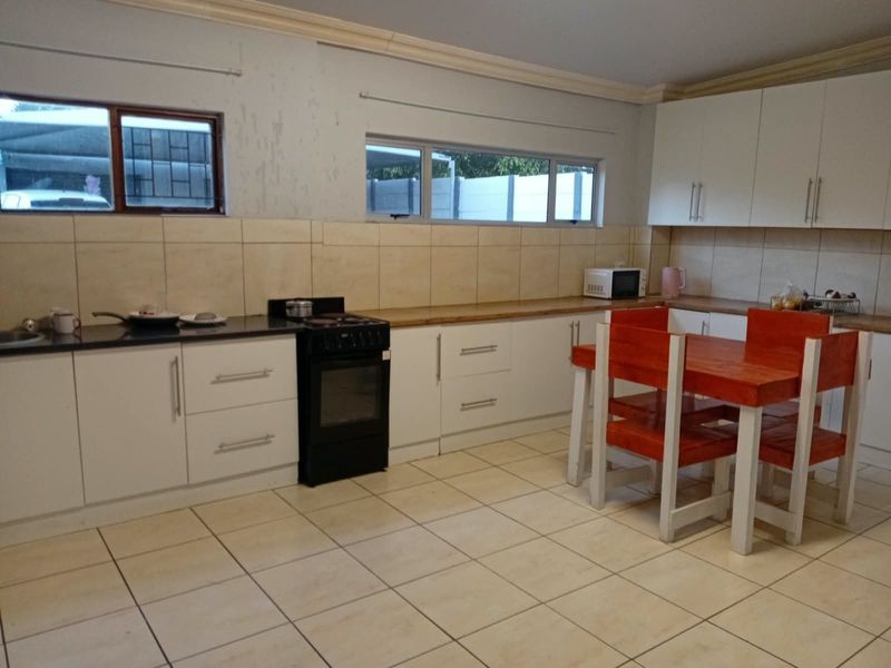 A functional kitchen featuring white cabinetry, tiled flooring, a tiled backsplash, and a freestanding stove, offering a practical layout for daily cooking and dining.