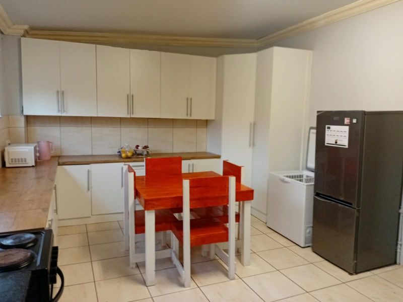A functional kitchen featuring white cabinetry, laminate countertops, tiled backsplash, and tiled flooring, providing ample storage and workspace.