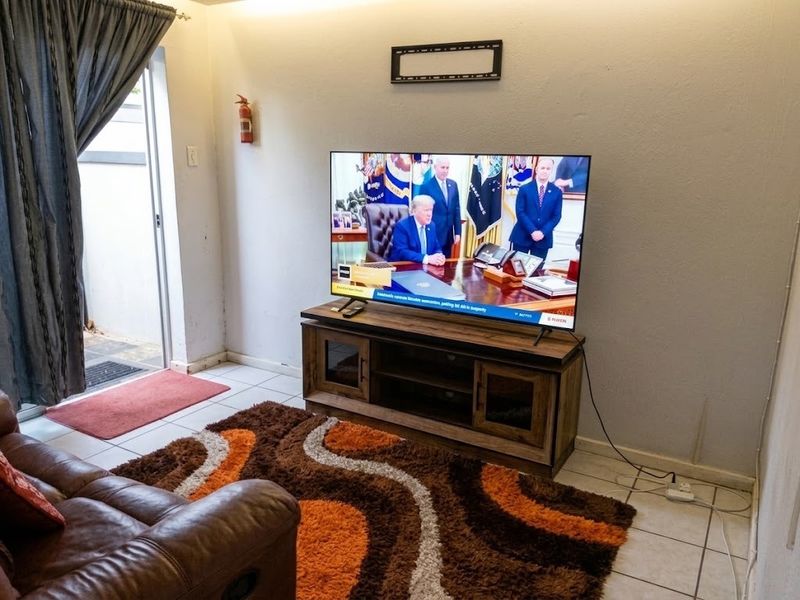 A living room area featuring tiled flooring, a sliding glass door providing outdoor access, and a wall-mounted fire extinguisher.