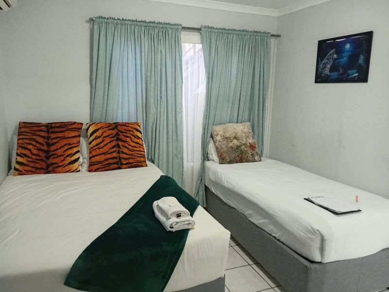 A functional bedroom featuring tiled flooring, an air conditioning unit, and window treatments.
