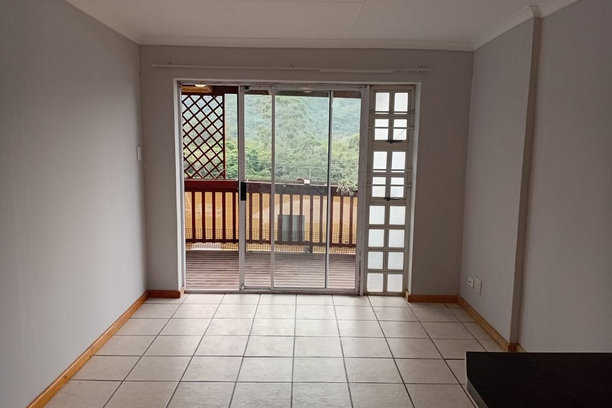 An empty living room featuring tiled flooring and a large sliding glass door providing access to an outdoor balcony area.