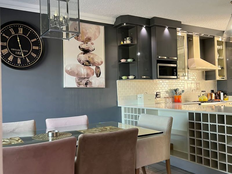 Modern open-plan kitchen and dining area featuring dark cabinetry, integrated wine storage, subway tile backsplash, and stylish pendant lighting.